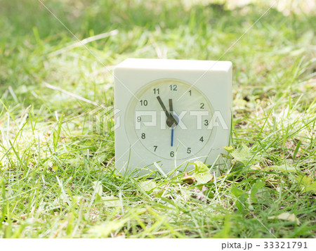 芝生の上の四角いシンプルな白い時計　11:55  33321791