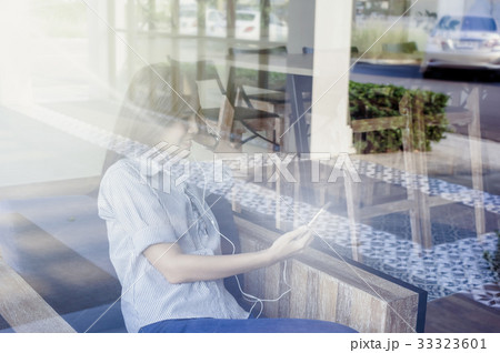 Businesswomen with casual suit using the smart phone in the coffee shop,shooting from out of windows, business technology concept 33323601