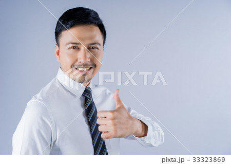 The asian man with thumbs up is smiling on gray background. 33323869