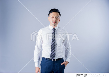 The asian businessman with formal suit is standing on gray background. 33323870