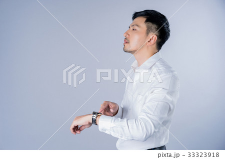 A man is touching his watch and looking something on gray background 33323918
