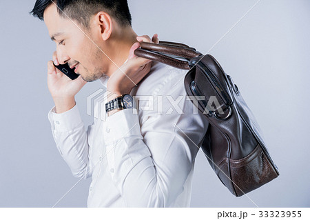 the businessman is carrying a bag and talking on a phone the businessman is carrying a bag and talking on a phone 33323955