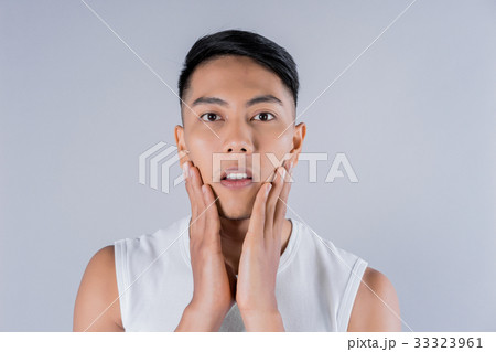 a man is massaging his face on gray background 33323961