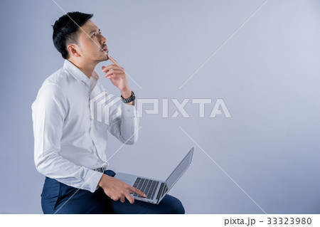 a businessman is using laptop and thinking on gray background a businessman is using laptop and thinking on gray background 33323980