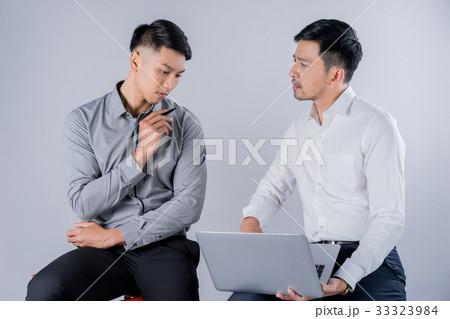 two business men are sitting and discussing something on laptop 33323984