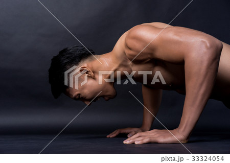 Portrait of a fitness man pushing up himself on black background 33324054