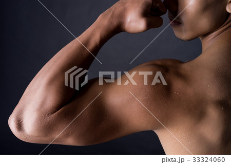 a photo of Asian body builder with his biceps on black background 33324060