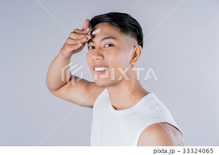 Young man is applying cream on his forehead 33324065