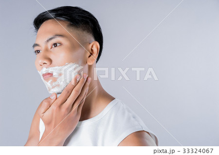 Young businessman is applying shaving cream on his face Young businessman is applying shaving cream on his face 33324067