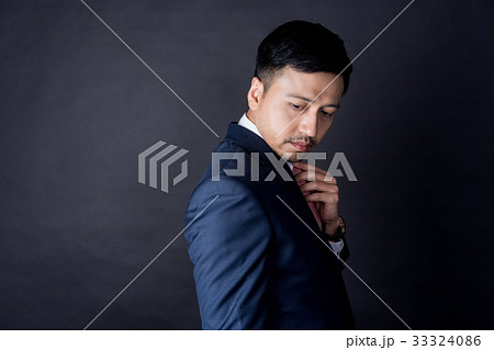 a businessman is touching his necktie and looking at something 33324086