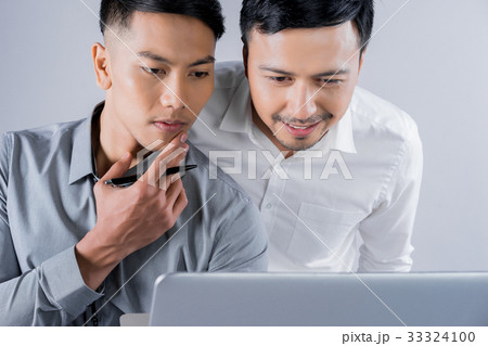 two young men are looking at laptop and thinking 33324100