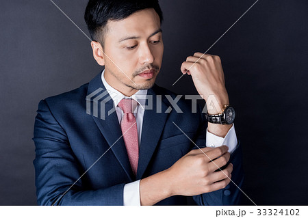 young businessman is adjusting his sleeve on black background 33324102