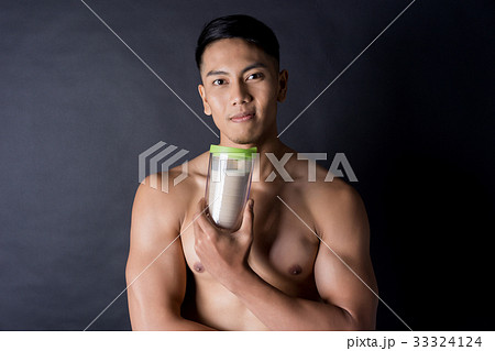 young bodybuilder is holding a protein shake on black background young bodybuilder is holding a protein shake on black background 33324124