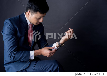 A portrait of man wearing suit and looking at the sleeve 33324131