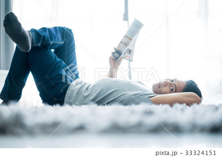 A photo of a man lying and reading newspaper A photo of a man lying and reading newspaper 33324151