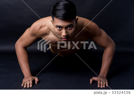 A portrait of muscle man doing exercise on black background 33324156