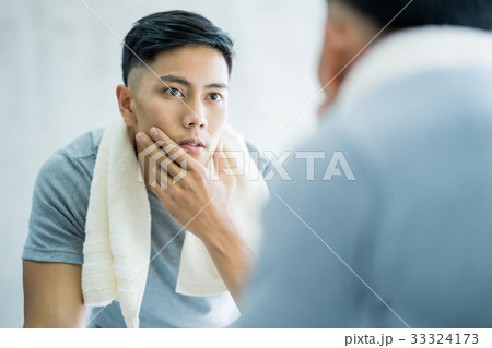 The portrait of man looking at the mirror and touching his face 33324173