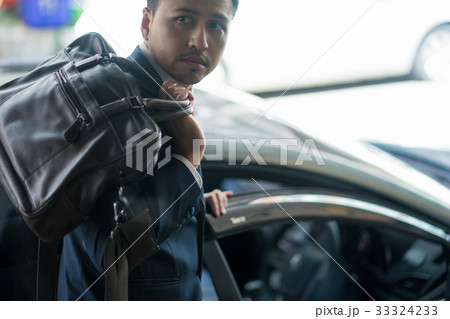 A portrait of businessman opening the car door while looking at something. A portrait of businessman opening the car door while looking at something. 33324233