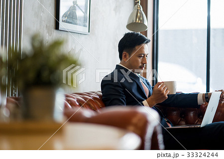 A portrait of young businessman drinking coffee while looking at the laptop. 33324244