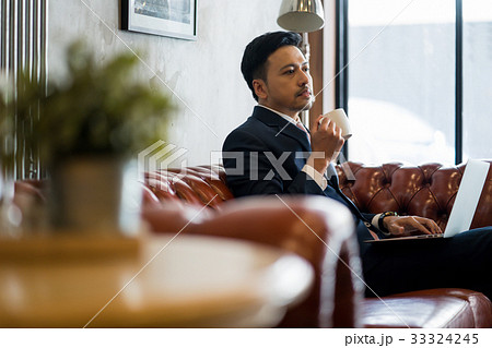 A handsome man is resting and drinking coffee on a sofa. A handsome man is resting and drinking coffee on a sofa. 33324245