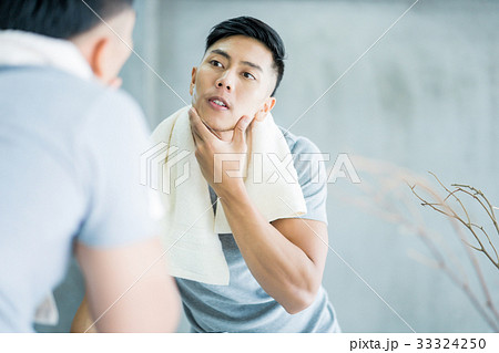 An handsome man is looking at his reflection in mirror in the bathroom. An handsome man is looking at his reflection in mirror in the bathroom. 33324250