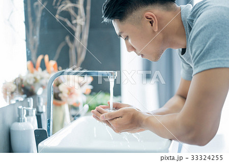 An Asian handsome man is preparing to wash his face in the bathroom. 33324255
