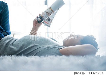 a man is lying on the bed and reading a magazine 33324264