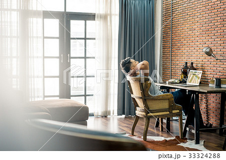 a photo of a man sitting on the chair and working a photo of a man sitting on the chair and working 33324288