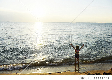 Silhouette rear view of young caucasian girl with arms raised at the beach alone 33331825