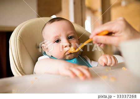 Unrecognizable mother at home feeding her baby son Unrecognizable mother at home feeding her baby son 33337268
