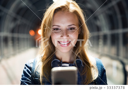 Woman in the city at night holding smartphone Woman in the city at night holding smartphone 33337378