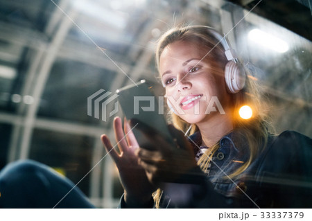 Woman in the city at night holding smartphone Woman in the city at night holding smartphone 33337379