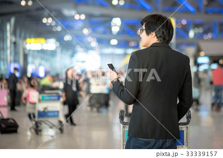 Asian man using smartphone in airport terminal Asian man using smartphone in airport terminal 33339157
