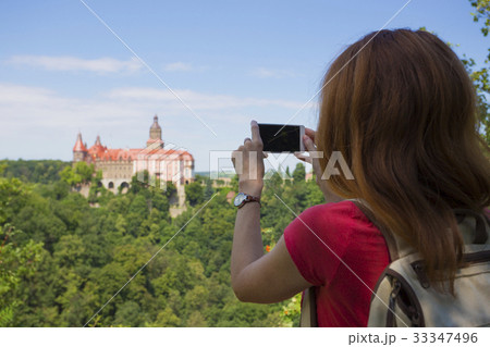 girl taking a picture of a beautiful castle on a hill 33347496
