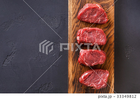 Raw beef filet mignon steaks on wooden board at Raw beef filet mignon steaks on wooden board at 33349812