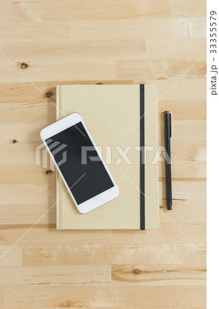 Directly above view of smart phone and personal organizer and pen on wooden desk 33355579