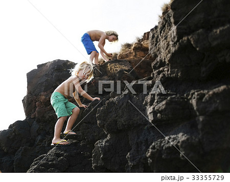 USA, Hawaii, Kauai, Boys (4-5, 8-9) climbing on rocks USA, Hawaii, Kauai, Boys (4-5, 8-9) climbing on rocks 33355729