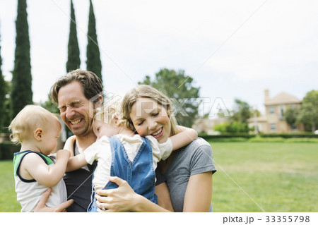 Parents with sons (12-17 months, 4-5) embracing in park 33355798