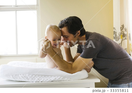 Father playing with baby boy (12-17 months) on changing mat Father playing with baby boy (12-17 months) on changing mat 33355811