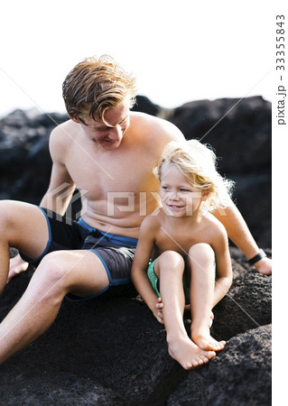 Young man with younger brother (4-5) sitting on rocks 33355843