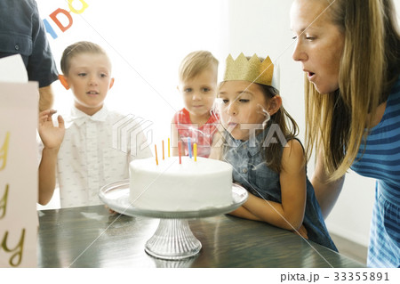 Brothers (2-3, 6-7) looking at sister (6-7) and mother blowing birthday candles 33355891