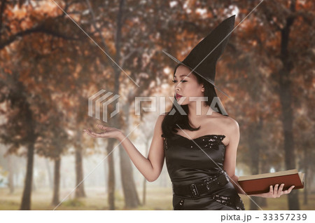 Asian woman in witch dress with open palm dan book 33357239