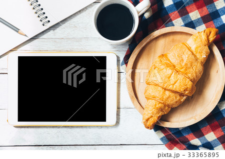 tablet with croissant and coffee on wooden table tablet with croissant and coffee on wooden table 33365895