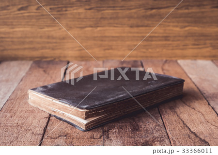 Old hardback book on wooden table. Old hardback book on wooden table. 33366011