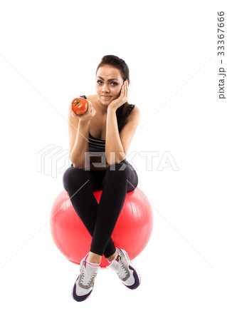 Girl is sitting on the fitness ball and holding a tomato 33367666
