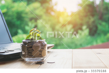 Coins put in glass and stack coins with laptop 33370188