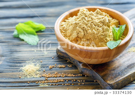 Ground mustard seeds in a wooden bowl. 33374130