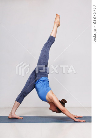 Woman doing Hatha yoga Eka pada adhomukha 33375757