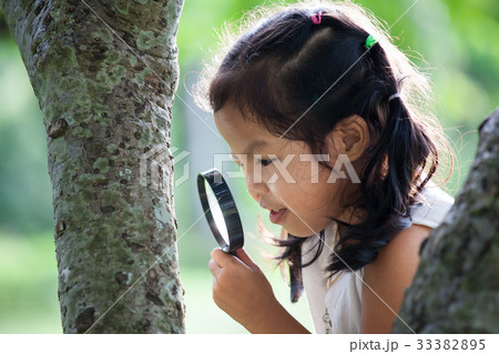 asian girl looking through a magnifying glass asian girl looking through a magnifying glass 33382895