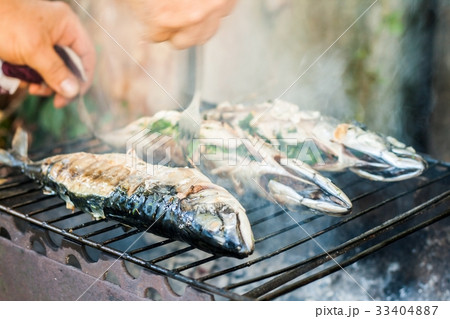 man checks the fish on the grill for readiness man checks the fish on the grill for readiness 33404887